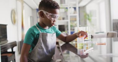 Video of african american boy doing experiments at home. Childhood, curiosity, education, spending free time at home concept.