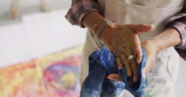 Video of biracial female artist cleaning hands with cloth. Art, crafts, creativity and creation process concept.