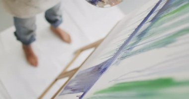 Video of legs of biracial female artist painting in studio. Art, crafts, creativity and creation process concept.