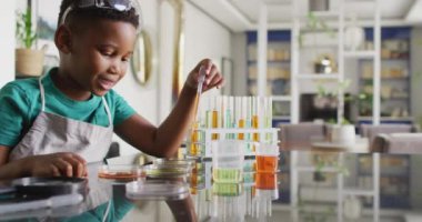 Video of happy african american boy doing experiments at home. Family, spending quality time together at home concept.