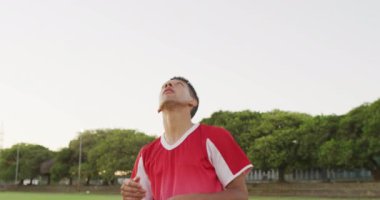 Video of biracial football player on field with ball. Male football team, inclusivity and fitness in team sports.
