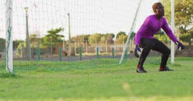 Video of african american football male goalkeeper with ball. Male football team, inclusivity and fitness in team sports.