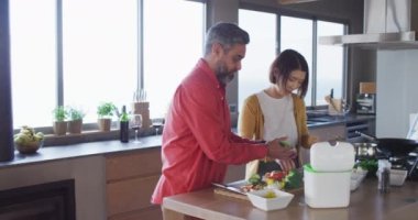 Birlikte yemek pişiren, sebze doğrayan ve mutfakta temizlik yapan mutlu çift. Evde kaliteli zaman geçirmek.