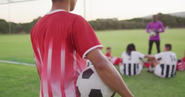 Video of biracial football player on field with ball. Male football team, inclusivity and fitness in team sports.