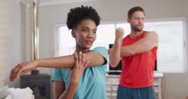 Video of focused diverse couple training together at home, stretching. Love, relationship and spending quality time together at home.