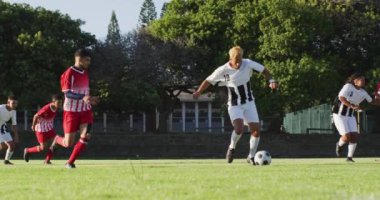 Video of diverse group of male football player on field, playing football. Male football team, inclusivity and fitness in team sports.