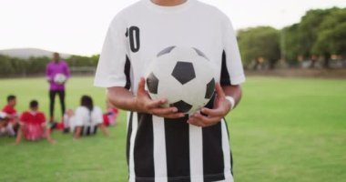 Video of biracial football player on field with ball. Male football team, inclusivity and fitness in team sports.