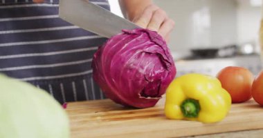Video of hands of caucasian man cutting cabbage in kitchen. Lifestyle, cooking, household and spending time at home concept.
