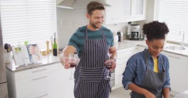Video of happy diverse couple preparing meal, cutting vegetables in kitchen. Love, relationship and spending quality time together at home.