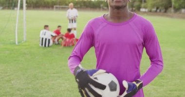 Video of african american football player on field with ball. Male football team, inclusivity and fitness in team sports.