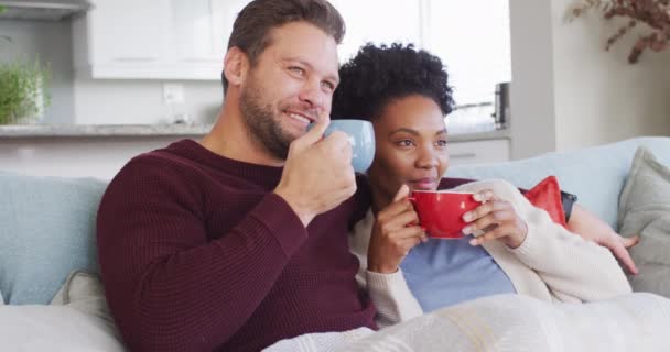 Video Happy Diverse Couple Embracing Drinking Coffee Sofa Love Relationship — Vídeos de Stock