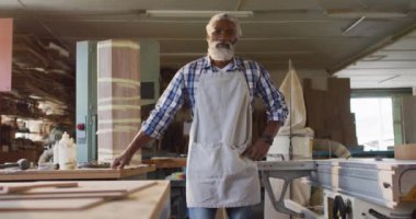 Portrait of african american male carpenter standing at a carpentry shop. Carpentry, craftsmanship and handwork concept