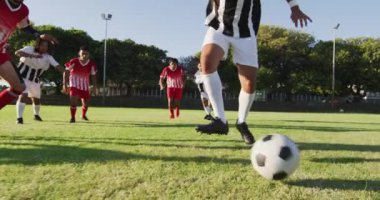 Video of diverse group of male football player on field, playing football. Male football team, inclusivity and fitness in team sports.