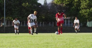 Video of diverse group of male football player on field, playing football. Male football team, inclusivity and fitness in team sports.