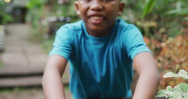 Portrait of happy african american boy planting in garden. Spending time outdoors, working in garden nursery.