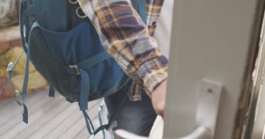 Diverse couple walking with baggage and hats and opening door. Spending quality time at home.