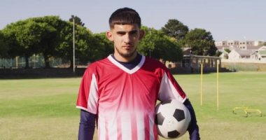 Video of biracial male football players with ball on field. Male football team, inclusivity and fitness in team sports.