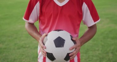 Video of biracial football player with ball on field. Male football team, inclusivity and fitness in team sports.