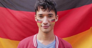 Portrait of happy biracial man with flag of germany in background and on cheek. Spending quality time at home.