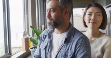 Happy diverse couple wearing casual clothes embracing together in kitchen. Spending quality time at home.