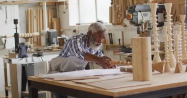 African american male carpenter keeping a wooden handicraft on workshop table at a carpentry shop. Carpentry, craftsmanship and handwork concept