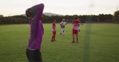 Video of diverse gorup of male football players on field,playing football. Male football team, inclusivity and fitness in team sports.