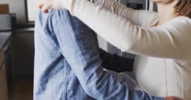 Mutfakta birbirine sarılan gündelik giysiler giyen mutlu çift. Evde kaliteli zaman geçirmek.