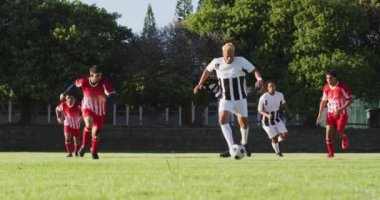 Video of diverse group of male football players on field, playing football. Male football team, inclusivity and fitness in team sports.