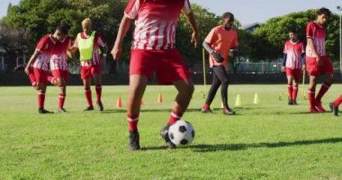 Video of diverse group of male football players warming up and kicking ball. Male football team, inclusivity and fitness in team sports.