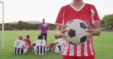 Video of biracial football player on field with ball. Male football team, inclusivity and fitness in team sports.