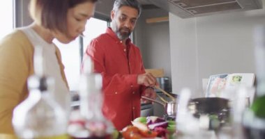 Birlikte yemek pişiren, mutfaktaki çömlek malzemelerini karıştıran mutlu çift. Evde kaliteli zaman geçirmek.