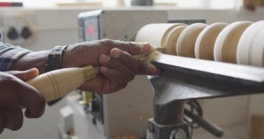 Close up of african american male carpenter hand's turning wood on a lathe at carpentry shop. Carpentry, craftsmanship and handwork concept