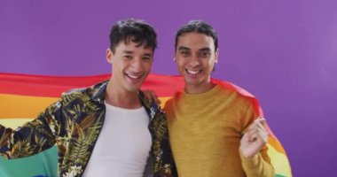 lgbt bayrağı tutan ve kucaklaşan mutlu erkek çiftin portresi. Evde kaliteli zaman geçirmek.