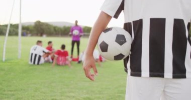 Video of biracial football player on field with ball. Male football team, inclusivity and fitness in team sports.