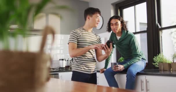 Happy Diverse Male Couple Drinking Coffee Using Smartphone Kitchen Spending — Vídeo de Stock