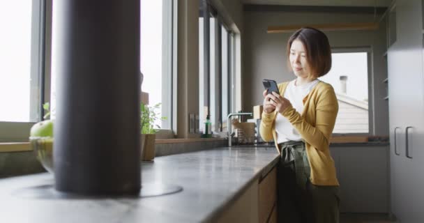 Asian Woman Wearing Jumper Using Smartphone Kitchen Alone Spending Quality — Αρχείο Βίντεο
