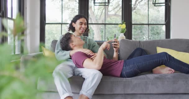 Happy Diverse Male Couple Sitting Sofa Embracing Using Smartphone Living — Stockvideo