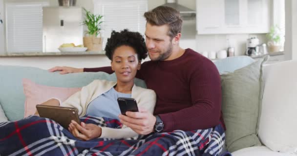 Video Happy Diverse Couple Embracing Using Electronic Devices Sofa Love — Vídeo de Stock