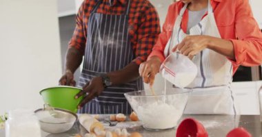 Video of happy african american couple baking together in kitchen. Love, relationship and spending quality time together concept.