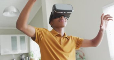 Evde VR kulaklık takan mutlu Afrikalı Amerikalı bir çocuğun videosu. Çocukluk, ev kavramında teknolojiyle zaman geçirmek..