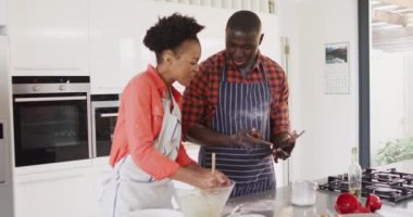 Video of happy african american couple baking together in kitchen. Love, relationship and spending quality time together concept.