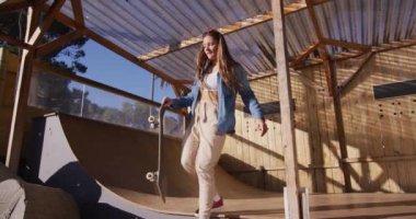 Video of happy caucasian female skateboarder training in skate park. Skateboarding, sport, active lifestyle and hobby concept.