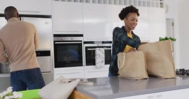 Video of happy african american couple unpacking groceries. Love, relationship and spending quality time together concept.