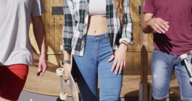 Video of midsection of diverse female and male skateboarders in skate park. Skateboarding, sport, hobby and active lifestyle concept.