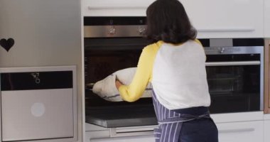 Video of happy asian woman taking out cake from oven. Lifestyle and spending time at home concept.