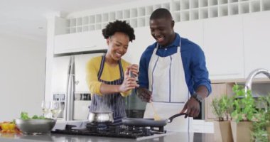 Video of happy african american couple cooking together. Love, relationship and spending quality time together concept.