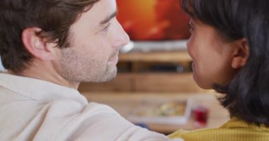 Video of happy diverse couple spending time together in living room. Love, relationship and spending quality time together concept.