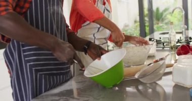 Video of happy african american couple baking together in kitchen. Love, relationship and spending quality time together concept.