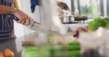 Video of hands of african american couple preparing meal together in kitchen. Love, relationship and spending quality time together concept.