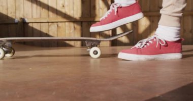 Video of midsection of caucasian female skateboarder training in skate park. Skateboarding, sport, active lifestyle and hobby concept.